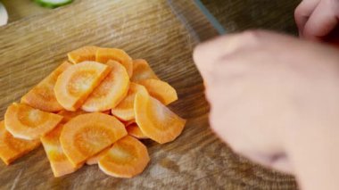 Kesme tahtasında taze havuç doğrayan kadın elleri, üst manzara.