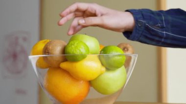 Sağlıklı atıştırmalıklar. Genç kadın mutfaktaki meyve tabağından taze elma alıyor, kesiyor ve yiyor.