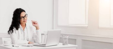 Office Work Concept. Happy hispanic businesswoman working on laptop in modern office, copyspace