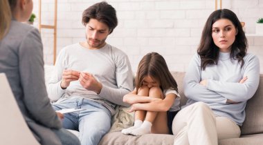 Aile danışmanlığı konsepti. Mutsuz adam ve kadın ve üzgün küçük kızları psikologların ofisinde oturmuş terapi görüyorlar.