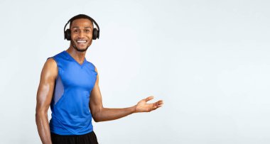 Genç siyahi sporcu, avuç içi açık elini uzatarak sarı stüdyo duvarını aşmaya davet ediyor.