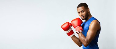 Dövüşçü. Atletik siyah adam boks duruşunda kameraya bakıyor, sarı stüdyo geçmişi var. Yan görünüm, boş alan