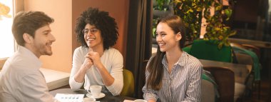 Neşeli çok ırklı iş ortakları restoranda yeni bir başlangıç projesi stratejisini tartışıyor, öğle yemeği yiyor, fotokopi çekiyor.