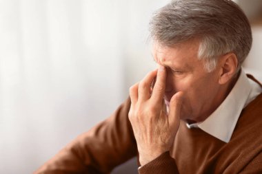 Yaşlılıkta depresyon. Evde koltukta oturan, Burun Köprüsü 'ne Dokunan Yalnızlığı Düşünen Umutsuz Yaşlı Adam. Boş Alan