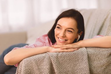 İyi eğlenceler Song. Kulaklıklı güzel bir kadının portresi kanepede uzanıyor ve evde müzik dinliyor.