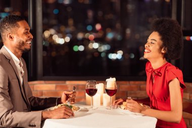 Romantizm randevusu. Sevgililer Günü 'nü kutlayan, akşam yemeği yiyen, gülen ve restoranda konuşan Afro çiftler..
