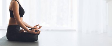 Bir kadın hasırda bacak bacak üstüne atarak oturur, sakin bir ifadeyle, parlak, barışçıl bir ortamda meditasyon yapar, uzayı taklit eder.