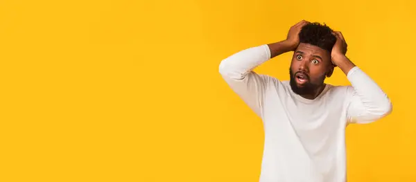 stock image Shocked african american guy with open mouth touching his head and looking at copy space, seeing shocking advertisement, panorama