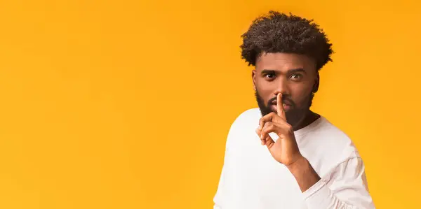 stock image Handsome silent african man making hush gesture, orange studio background