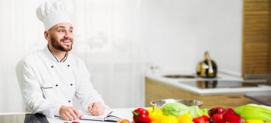 Şef Adam kendi yemek tarifleri yazıyor. Restoran mutfağında kendi yemek kitabı üzerinde çalışıyor. Seçici Odaklanma