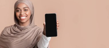 Elinde boş siyah ekran ile modern akıllı telefon tesettürlü Afrikalı Müslüman kız, boş alan ile sarı arka plan