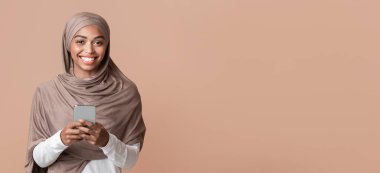 Modern İletişim Konsepti. Akıllı Telefonlu Neşeli Afro Müslüman Kız Portresi Kameraya, Sarı Arkaplana Bakıyor, Boşluğu Kopyala