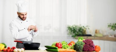 Yemek pişirme konsepti. Erkek aşçı biber ve baharat ekliyor. Mutfak içinde baharat ve çeşnili yemekler. Seçici Odaklanma