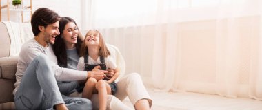 Aile Aşkı. Oyuncu ebeveynler küçük kızlarını gıdıklıyor, evde birlikte eğleniyorlar, boş yer var.
