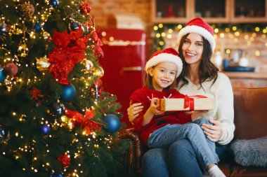 Mutlu küçük kız arzulanan Noel hediyesini tutuyor, evde ailesiyle Noel 'i kutluyor.