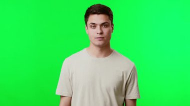 Genç bir adam açık yeşil bir ekranın önünde iki eliyle hareket ediyor. Meşgul ve canlı görünüyor, muhtemelen bir fikir veya temayı temsil ediyor..
