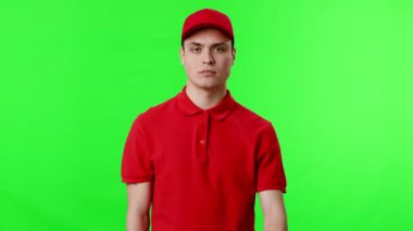 Kırmızı polo tişörtlü ve şapkalı genç bir adam durdurma hareketi için elini kaldırdı. Parlak yeşil arka plan olay yerine canlı bir ton ekliyor, görsel etkiyi arttırıyor..