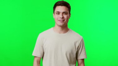 Genç bir adam kutlama için kollarını kaldırırken sevinçten havalara uçar. Parlak yeşil bir arka planın önünde duruyor, mutluluk ve pozitiflik saçıyor..