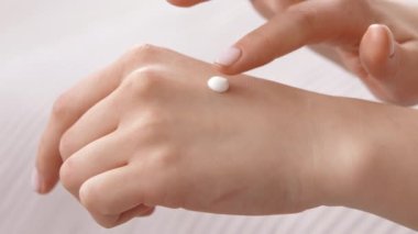 Bir insan eline az miktarda nemlendirici krem sürerek cilt hidrasyonuna odaklanır. Bu rutin, gün boyunca cilt bakımını ve beslenmeyi ön plana çıkarır..