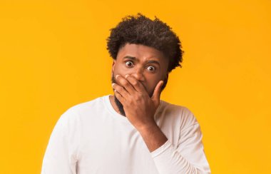 Hadi canım. Avuç içi turuncu arka plan ile ağzını kapatan geniş açık gözlü afro bir adam.