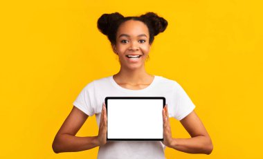 Stüdyoda boş tablet bilgisayar ekranı gösteren genç siyah kız. Panorama, boşluk