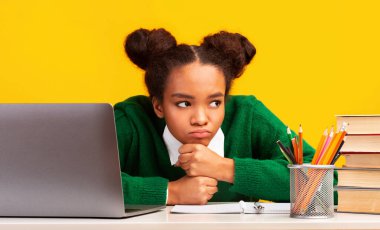 Lack Of Motivation. Bored black girl sitting at table, teenager doesnt want to study, yellow background, free space clipart