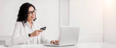 Easy Payment. Happy brazilian businesswoman working and buying online with credit card and laptop. Free space