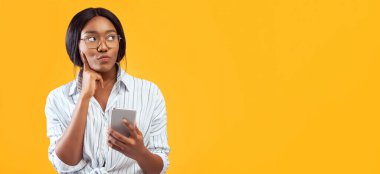 Akıllı Telefon kullanan düşünceli Afrikalı Amerikalı kız Pembe Stüdyo 'nun arkasında duran bir şeyi düşünüyor. Boş Alan