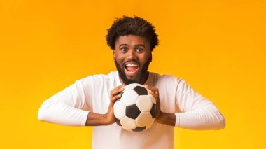 Heyecanlı Afro-Amerikan futbol fanatiği. Top turuncu arka planda, kopyalama alanı.