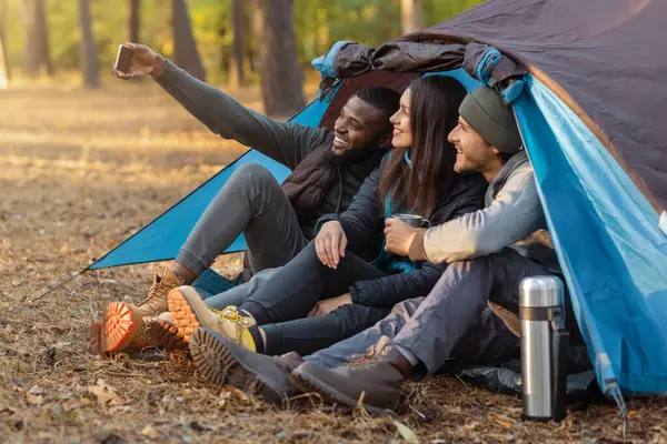 Uluslararası turist grubu kamp çadırında selfie çekiyor.