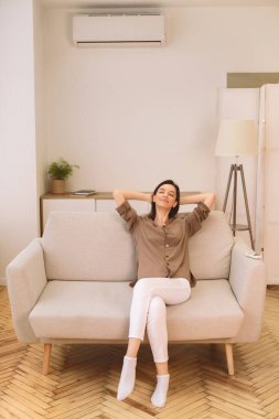 Tembel hafta sonu. Mutlu genç kadın evdeki kanepede dinleniyor klimanın altında, geriye yaslanıyor, kopyalanmış alan