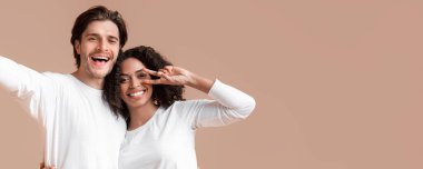 Romantic Mixed-Race Couple Taking Selfie. Cheerful Black Girlfriend Gesturing Peace Sign And Cuddling With Her Boyfriend, Yellow Background