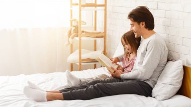 Baba ve küçük kızı hafta sonunu evde birlikte geçiriyorlar, kitap okuyorlar, yatakta oturuyorlar, fotokopi çekiyorlar.