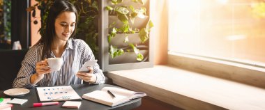 İş çizelgeleri üzerinde çalışıyor. Bin yıllık kadın arıyorum smartphone ve kahve içme, kafede, pazarlama analiz yapma, boş alan