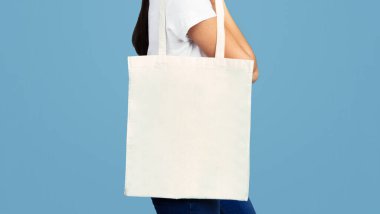 Tanımlanamayan Kız Boş Beyaz Eko Torbası Stüdyoda Mavi Arkaplanda Duruyor. Panorama, Kırpılmış