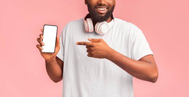 Kulaklığı boş akıllı telefon ekranına doğrultulmuş afro bir adamın kesilmiş fotoğrafı, müzik uygulaması öneriyor, panorama