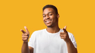 Sana ihtiyacım var. Turuncu arka plan, panorama ve boş alan üzerinde izole edilmiş mutlu afro adam kamerayı işaret ediyor.