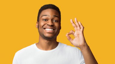 Her şey yolunda. Mutlu Afro-Amerikan adam onay jesti ve gülümsüyor, turuncu stüdyo geçmişi var.