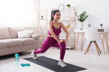 Evde kal, aktif kal. İspanyol kız oturma odasında kardiyo çalışması yapıyor.