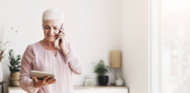 Evde dijital tablet okuyup müşteriye danışmanlık yapmakla meşgul olan yaşlı kadın, boşluğu kopyala