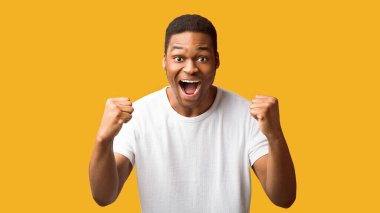 Büyük şans. Heyecanlı siyahi adam sevinçten çığlık atıyor. Kazanan jest yapıyor. Turuncu duvar, panorama ve telif boşluğundan izole edilmiş.