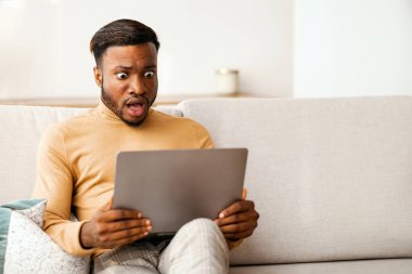 Evdeki koltukta oturan siyahi adam dizüstü bilgisayara bakıyor. Seçici Odaklanma