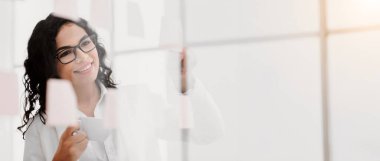 Strateji Atölyesi. Kendine güvenen Meksikalı yönetici ofis duvarındaki yapışkan notlar hakkındaki fikirlerini paylaşıyor.