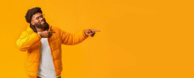 Gözlüklü bir Afrikalı, turuncu arka plan ve panorama üzerine yeni bir teklif sunuyor.