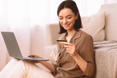 Çevrimiçi bankacılık. İnternette ödeme yapmak için laptop ve kredi kartı kullanan mutlu bir kız.