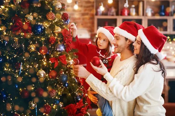 Heyecanlı genç bir aile Noel arifesinden önce evde Noel ağacı yapıyor, boşluğu kopyalıyor.