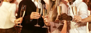 Mutlu noeller. Tanınmayan insanlar ellerinde şampanya bardakları tutuyorlar. Şirket içinde Noel 'i kutluyorlar. Panorama, Kırpılmış, Seçici Odaklanma