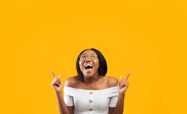 Şuraya bak. Heyecanlı Afro Kadın Boş Alan 'ı Gösteriyor Turuncu Arkaplan' ın üzerinde duruyor. Stüdyo Çekimi