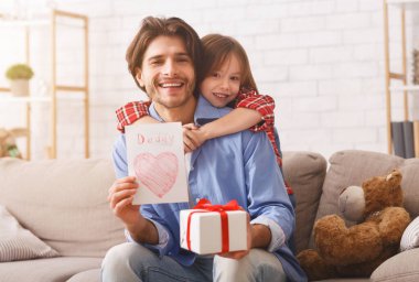 Mutlu bir baba ve küçük kızı evde babalar gününü kutluyor, elinde hediye kutusu ve kartı olan bir adam, bedava yer.