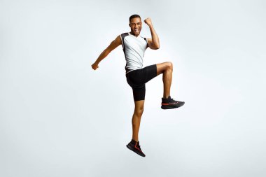 Bir Numara. Heyecanlı siyahi sporcunun tam boy portresi zaferi kutluyor kırmızı stüdyo arkaplanından atlıyor